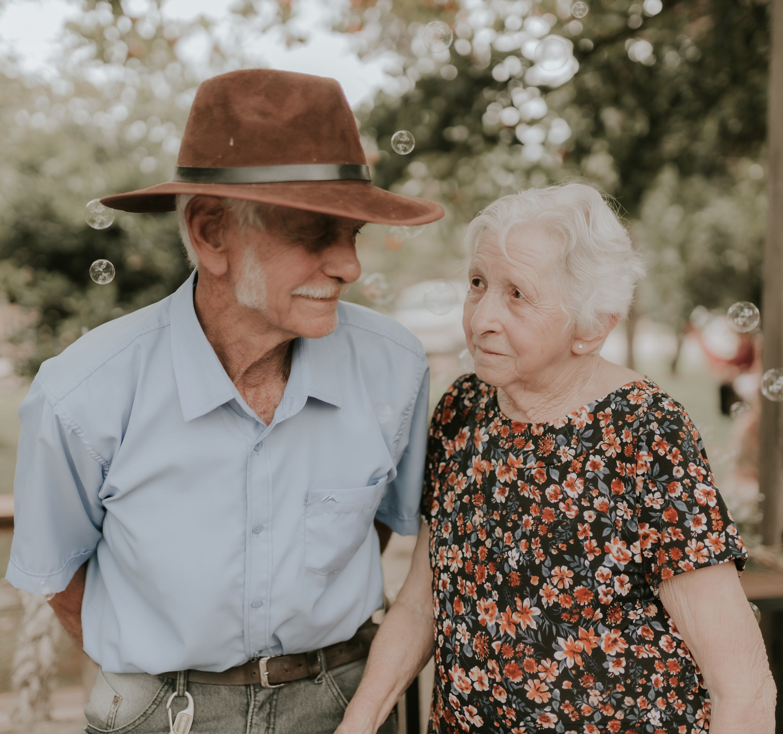 An endearing elderly couple sharing a joyful moment outdoors with bubbles in the air.